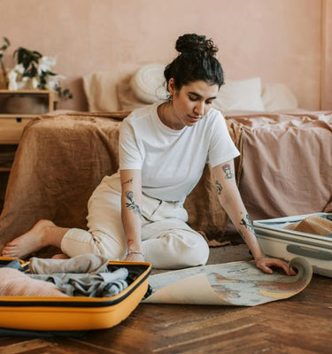 Une femme en train de préparer sa trousse de toilette et sa valise pour voyager.